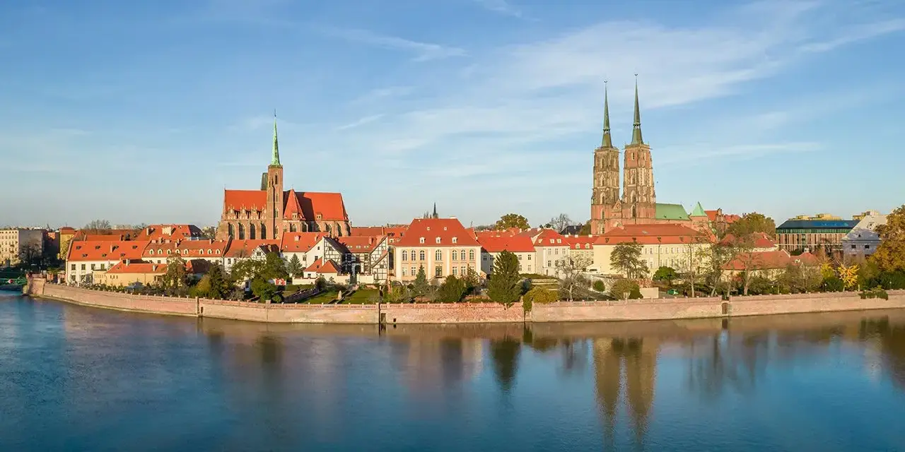 Wrocław stare miasto z katedrami i Ostrów Tumski nad Odrą, odbijające się w spokojnej wodzie.