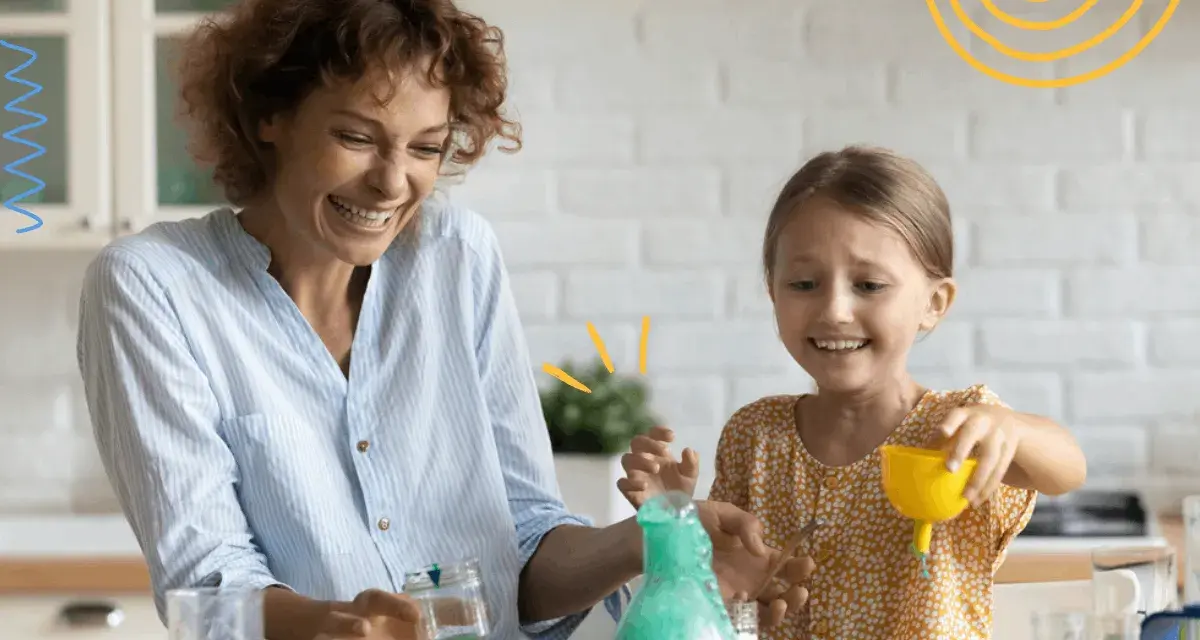 Mama i córka śmieją się, wykonując spektakularne eksperymenty dla dzieci z zieloną pianą w probówce.