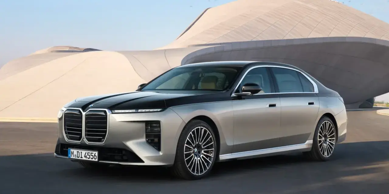 Elegancki BMW 740d w dwukolorowym malowaniu, zaparkowany przed nowoczesnym budynkiem.