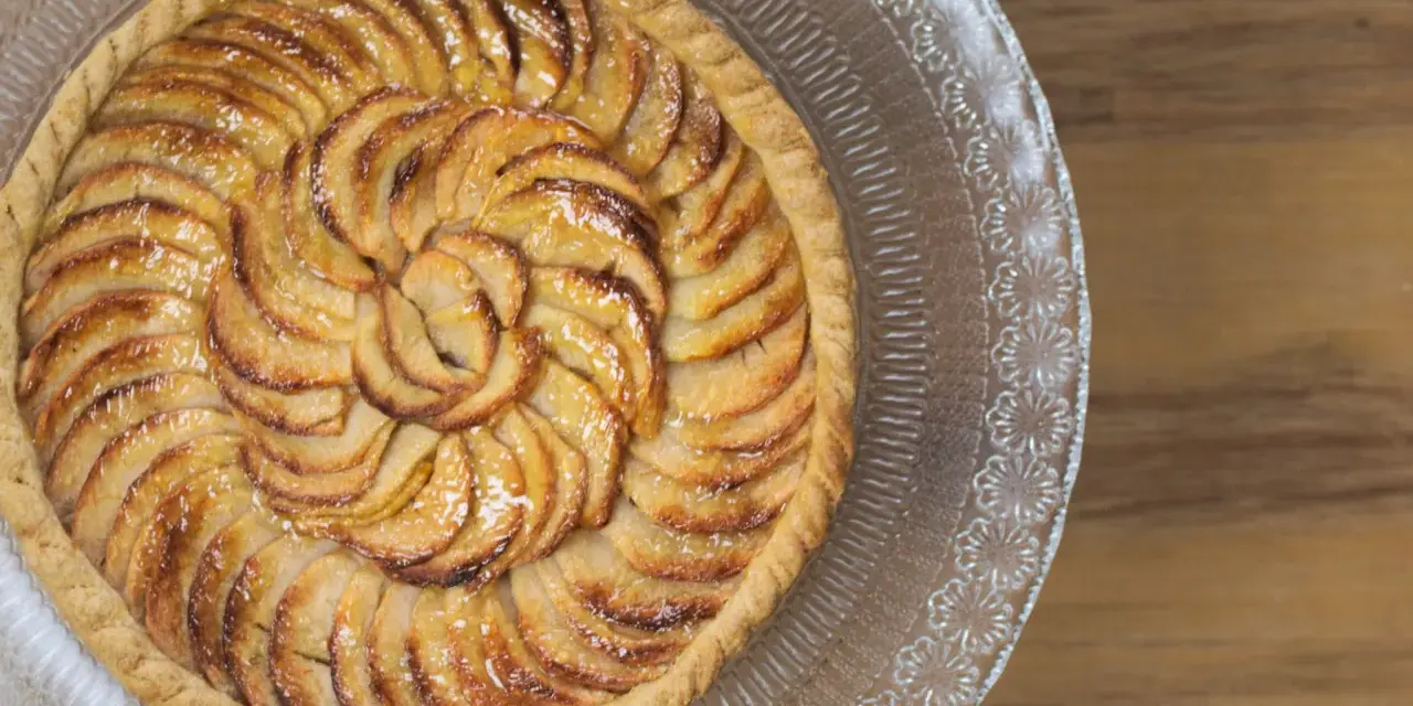 Tarte aux pommes dorée sur un plat en verre, parfaite pour une recette gâteau avec pâte feuilletée facile.