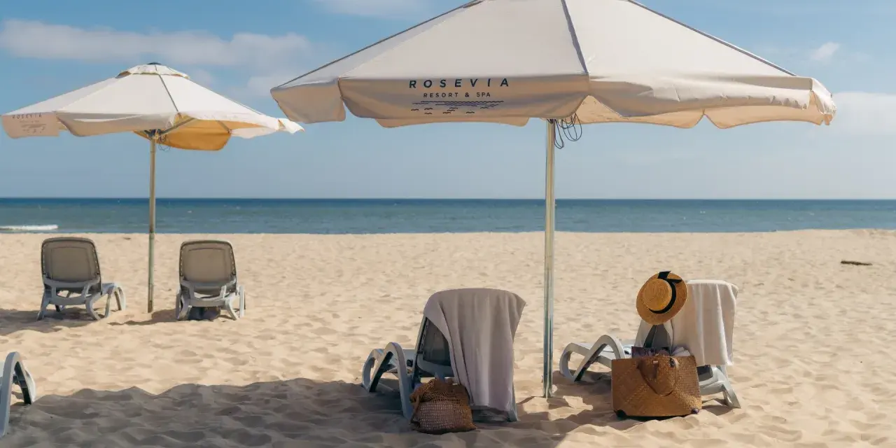 Leżaki i parasole na piaszczystej plaży nad morzem.
