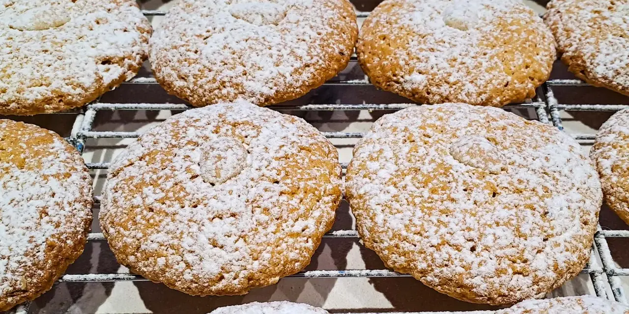 Deliziosi biscotti con farina di mandorle, cosparsi di zucchero a velo, riposano su una griglia.