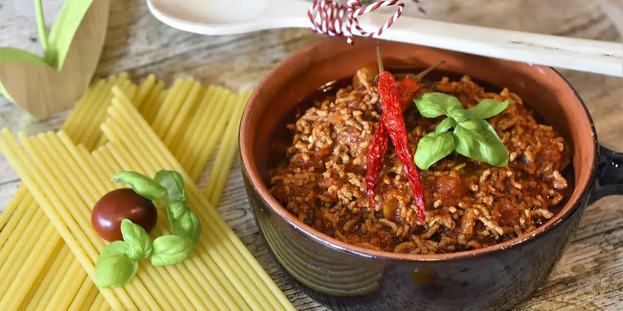 Un invitante ragù, pronto per la pasta, con peperoncini e basilico. La ricetta perfetta per un pranzo gustoso.