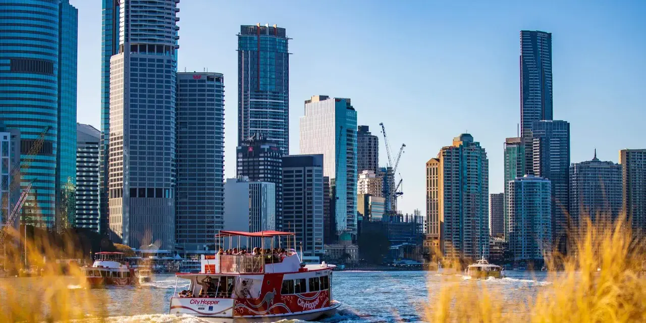 Ein Auslandssemester in Australien: Boote auf dem Fluss vor der Skyline von Brisbane mit modernen Hochhäusern.