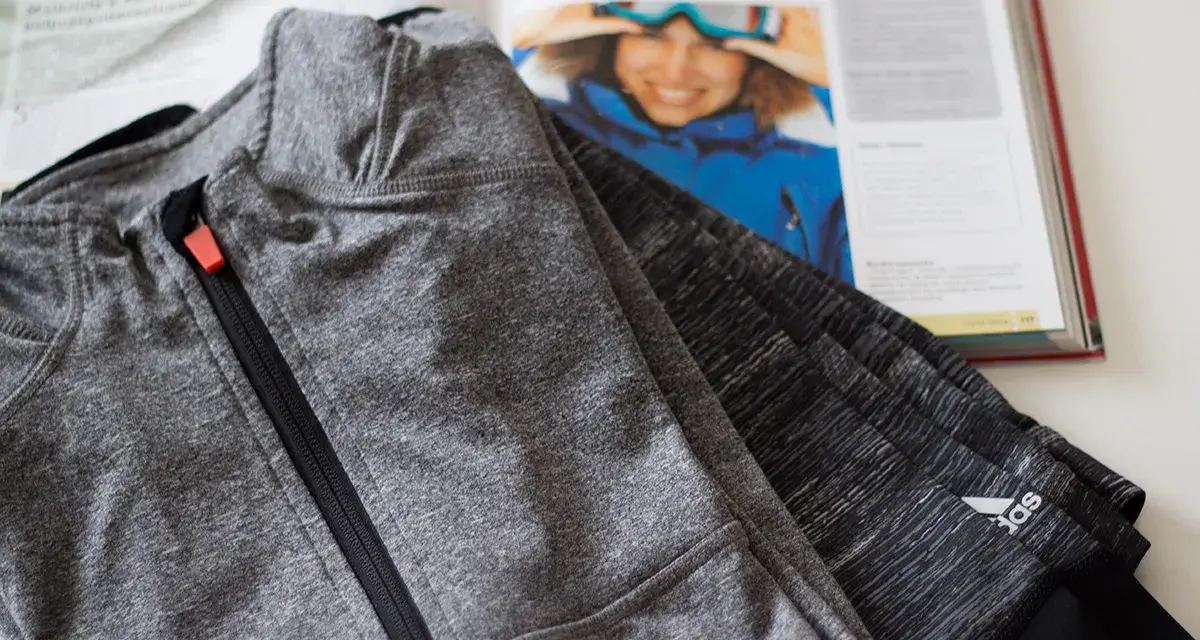Szara bluza sportowa z zamkiem i logo Adidas. Czy poliester się rozciąga? Tak, ten materiał jest elastyczny.