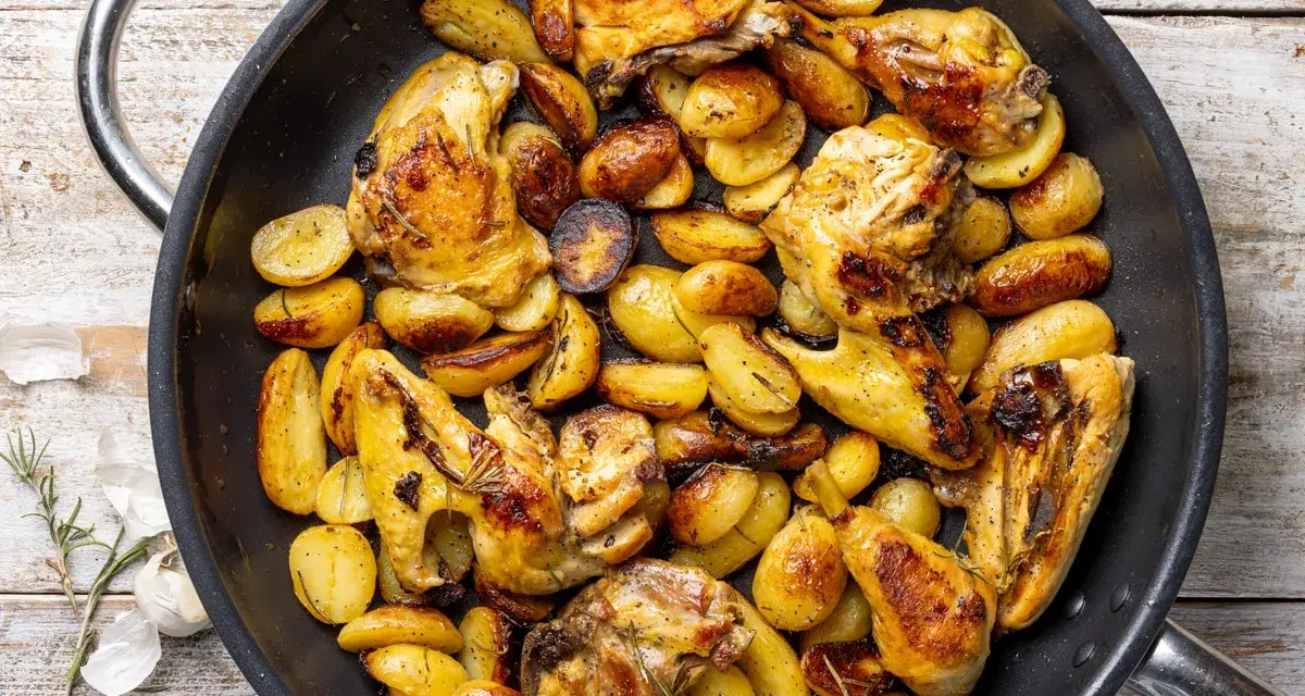 Pollo con patate in padella, dorato e saporito, con erbe aromatiche. Un piatto rustico e invitante.