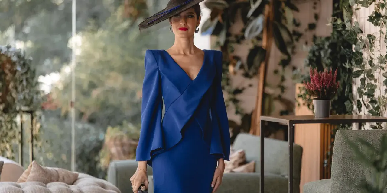 Elegante mujer con vestido azul klein y sombrero, ideal para saber como combinar un vestido azul klein para una boda.