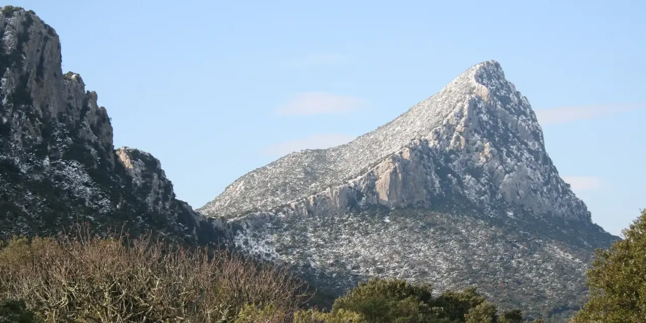 Vue hivernale du pic Saint-Loup, ses pentes couvertes de neige contrastant avec le ciel bleu.