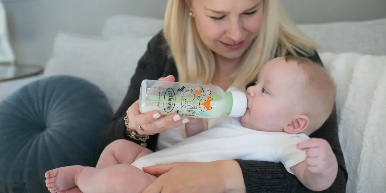 Mama karmi dziecko z butelki antykolkowej Dr Brown's z uroczym motywem lisów.