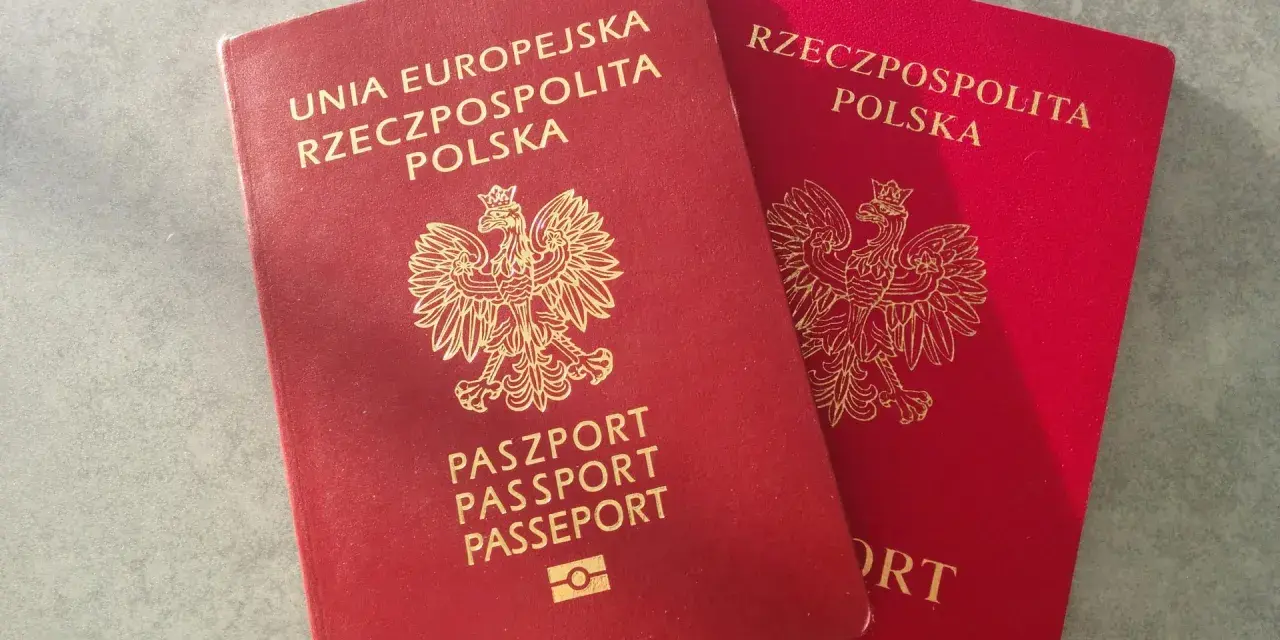 Dwa polskie paszporty w kolorze czerwonym leżą obok siebie na szarym tle.