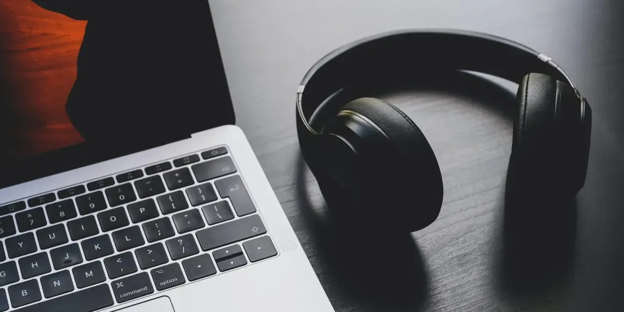 Słuchawki leżą obok laptopa. Może to być sygnał, że występuje brak dźwięku w laptopie i potrzebne są słuchawki do słuchania.