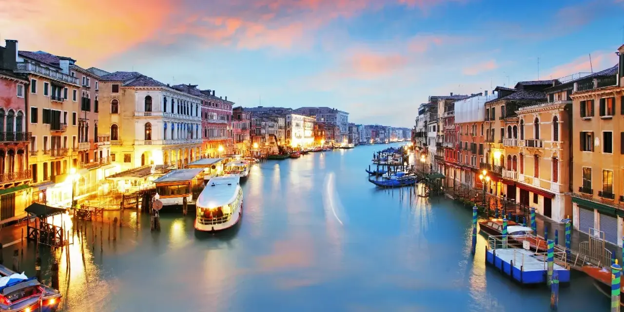 Il Canal Grande di Venezia, con le sue opere d'arte architettoniche illuminate al tramonto, accoglie gondole e vaporetti.