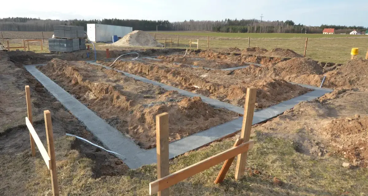 Rozpoczęto wylewanie fundamentu pod nowy dom. Wykopano rowy, w których widać świeży beton.