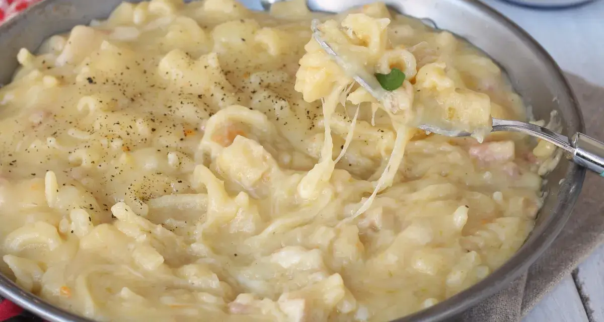 Una padella piena di cremosa pasta con patate, condita con pepe nero. Un piatto confortante e saporito.