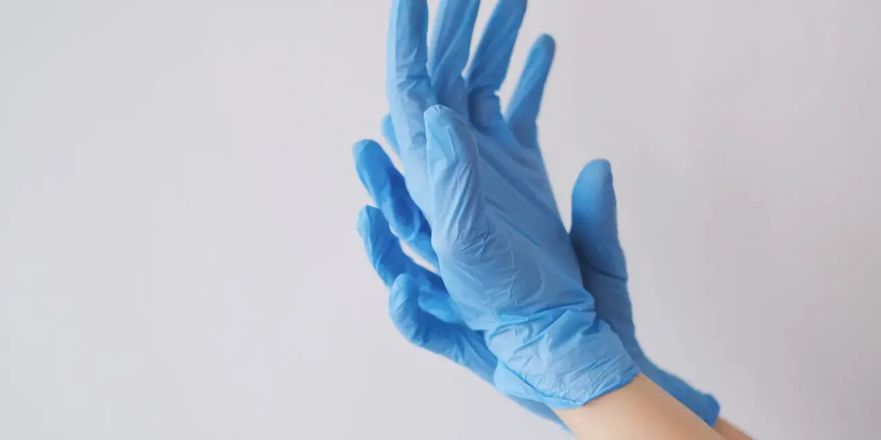Ręce w niebieskich rękawiczkach nitrylowych, idealnych jako rękawiczki do laboratorium chemicznego.