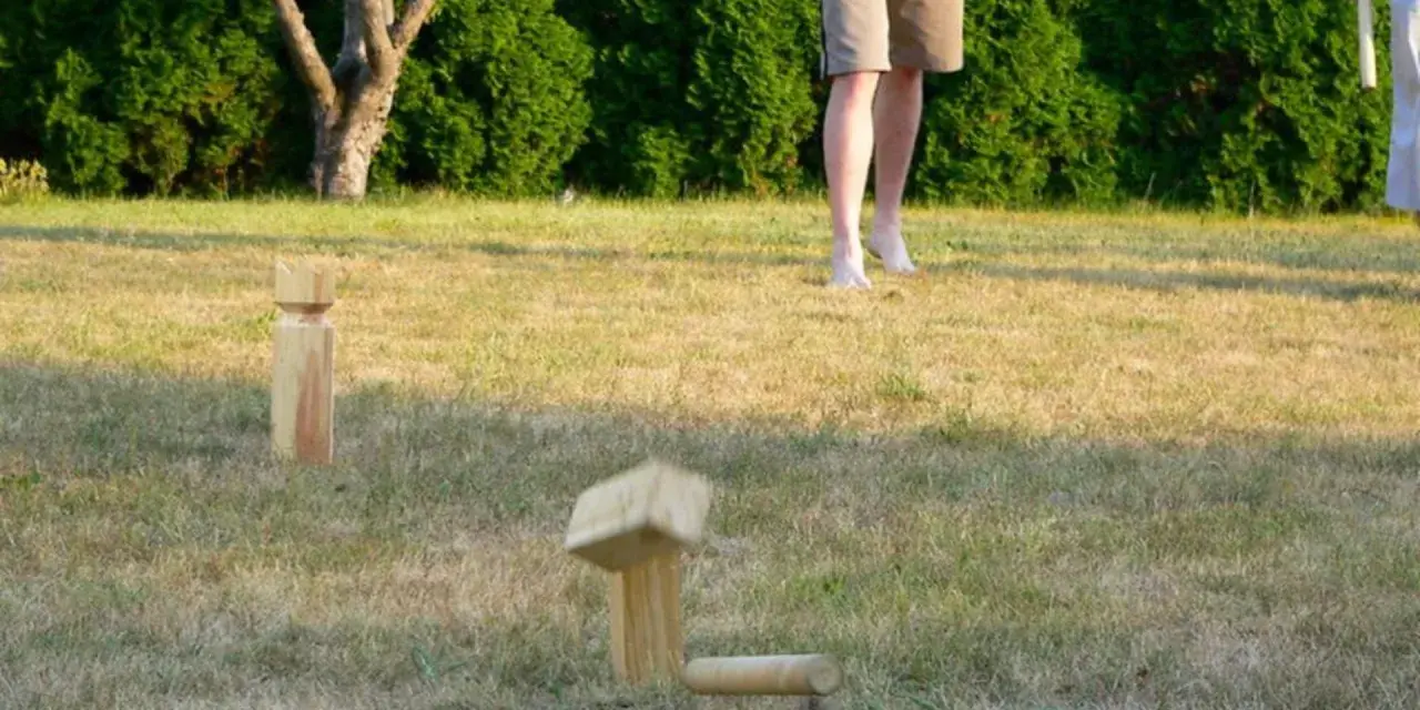 Holzfiguren für Outdoor-Spiele im Gras. Ein Spielstein ist in der Luft, bereit für das nächste Spiel.
