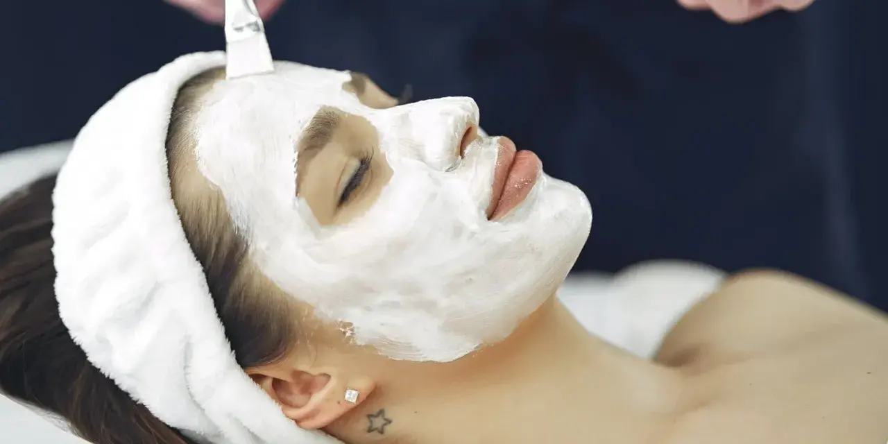 A woman receives a soothing facial mask application. This is a relaxing facial vs massage experience.