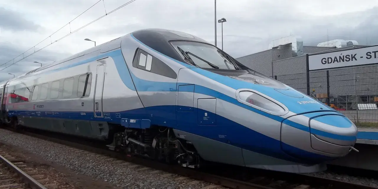 Nowoczesny pociąg Pendolino w kolorach biało-niebieskim stoi na torach przy peronie.