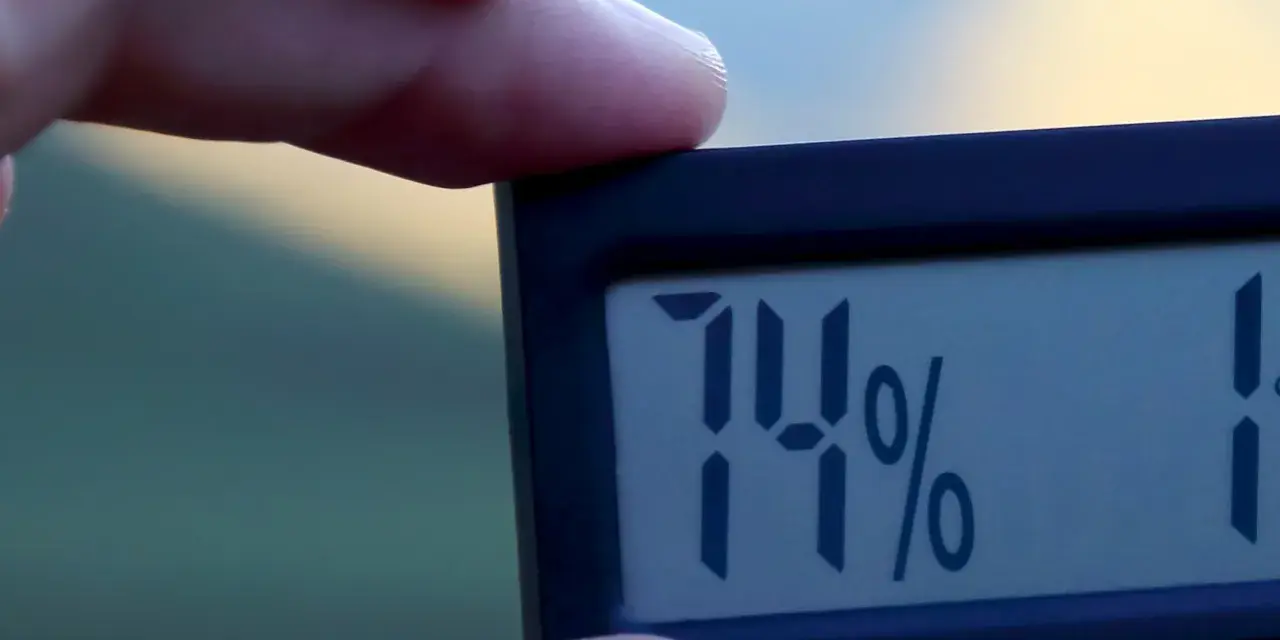En digital hygrometer visar 74%, vilket indikerar normal luftfuktighet inomhus.