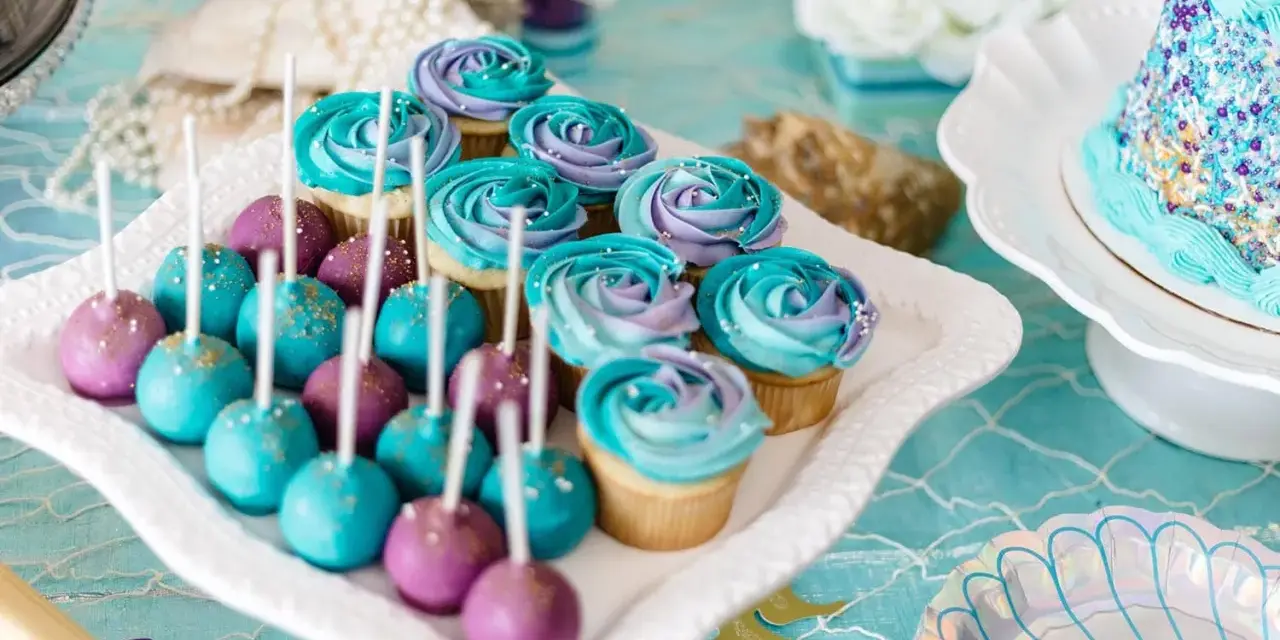 Söta cupcakes och cake pops i lila och turkost, perfekta att köpa till babyshower. Havstema med pärlor och snäckskalsformade tallrikar.