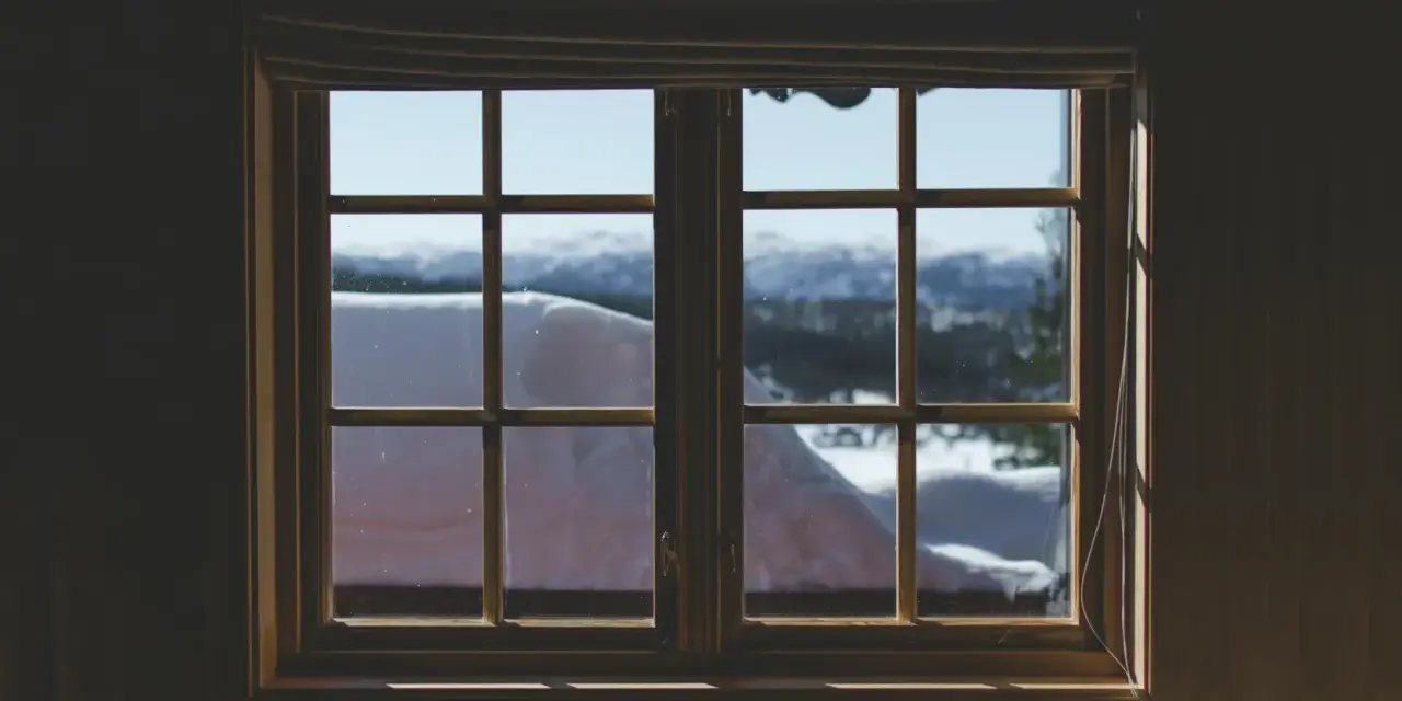 Finestra con infissi in legno, vista su paesaggio innevato. Ideale per chi vuole rinnovare infissi in legno fai da te.