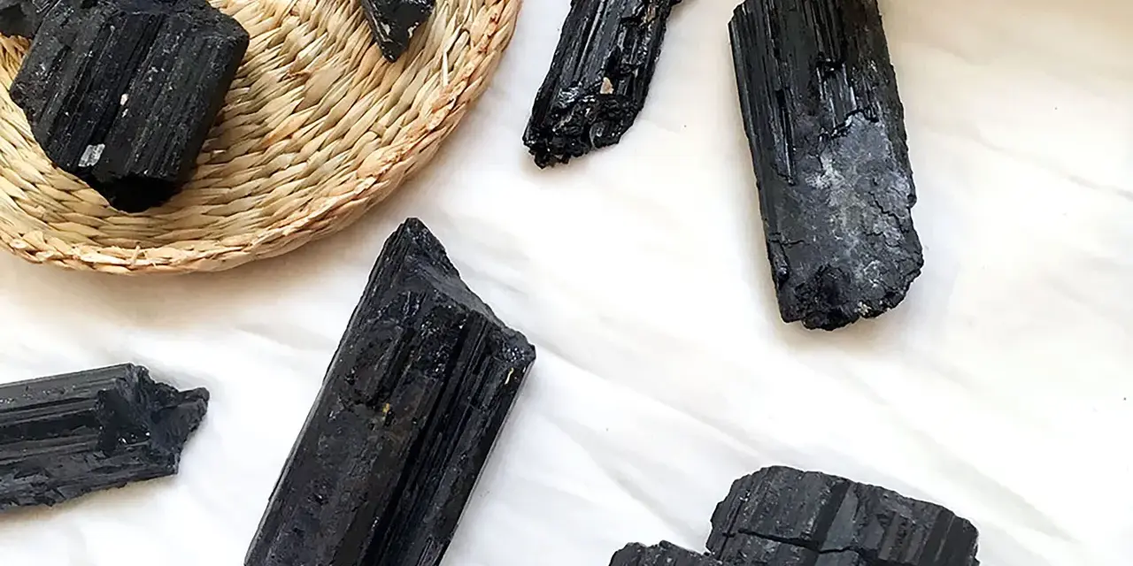 Cristales de turmalina negra, algunos en una cesta de mimbre, listos para atraer el amor y la protección.