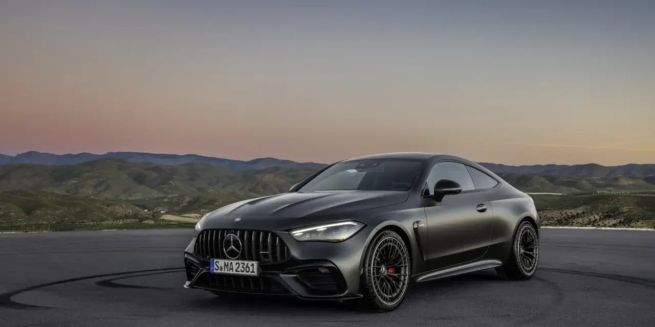 Ciemnoszare coupé Mercedes-AMG CLE 53 na tle górskiego krajobrazu o zachodzie słońca.