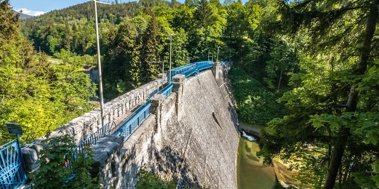Kamienna zapora w otoczeniu zielonych gór. Spacer po koronie zapory to jedna z wielu międzygórze atrakcje, oferująca piękne widoki.