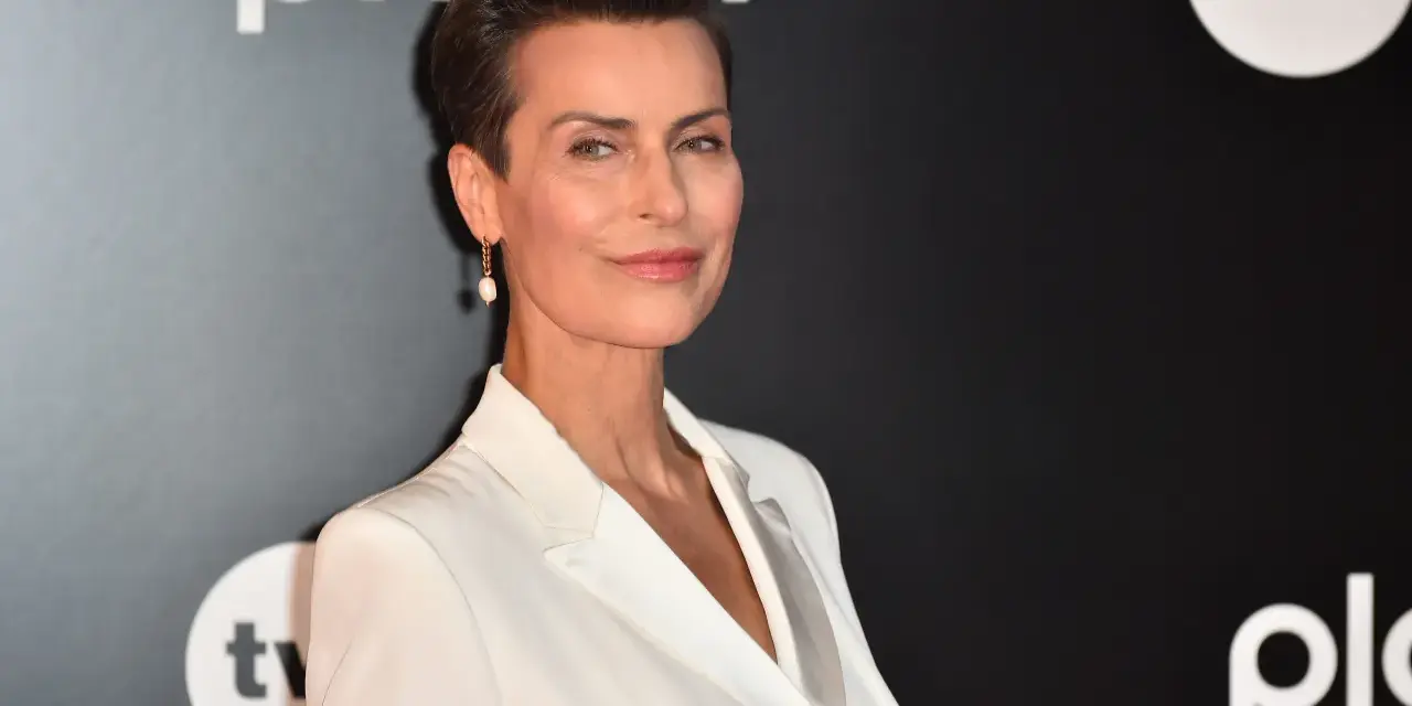 Danuta Stenka w białej kreacji, gwiazda filmów, seriali i programów, na tle logo TVN i Playera.