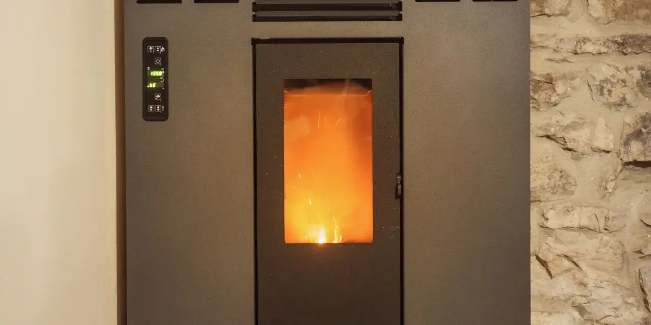 Stufa a pellet con fiamma viva visibile. Il pannello di controllo mostra "19.5°". La distanza candeletta stufa pellet è ottimale per l'accensione.