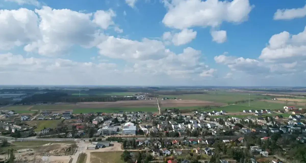 Krajobraz z zabudowaniami i polami. Działki rolne z możliwością zabudowy zagrodowej są teraz najbardziej poszukiwane, bo łączą spokój wsi z potencjałem rozwoju.