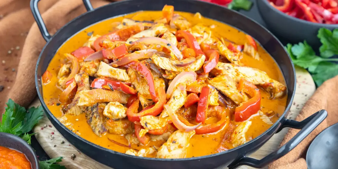 Ein einfaches Putengeschnetzeltes-Rezept mit Paprika und Zwiebeln in cremiger Sauce, serviert in einer Pfanne.