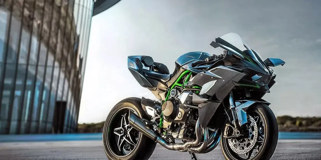 Kawasaki H2R – maszyna, która w mgnieniu oka osiąga 100 km/h. Czarny, sportowy motocykl z zielonymi akcentami na ramie, zaparkowany przed nowoczesnym budynkiem.