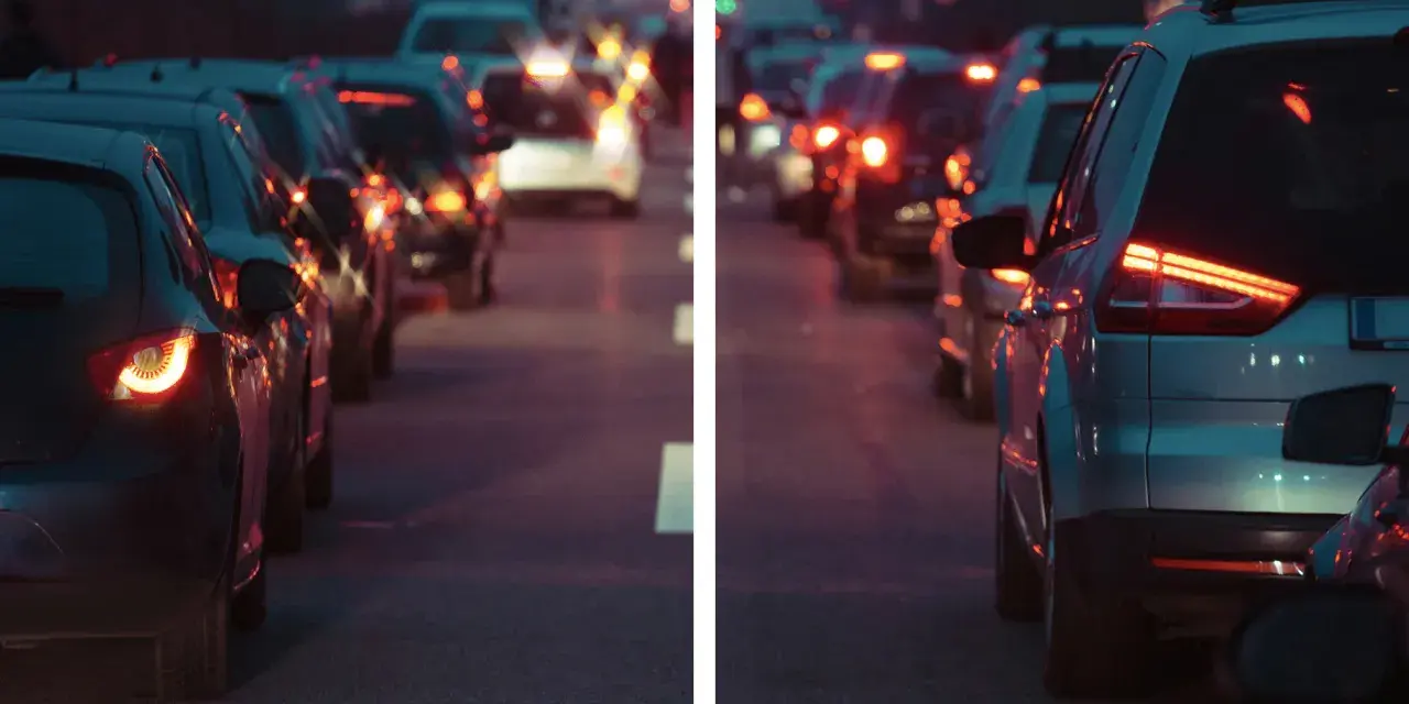 Traffico serale con luci sfocate, come vede le luci un miope. Le auto ferme creano un effetto di aloni luminosi.