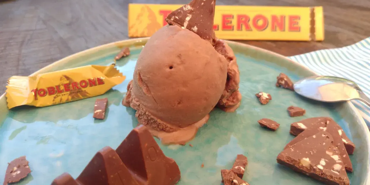 Schokoladeneis mit Toblerone-Stücken und einer ganzen Toblerone-Tafel auf einem Teller.