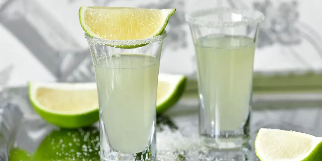 Dwa kieliszki z drinkiem Kamikadze, ozdobione solą i plasterkami limonki. Idealny przepis na orzeźwiający shot.