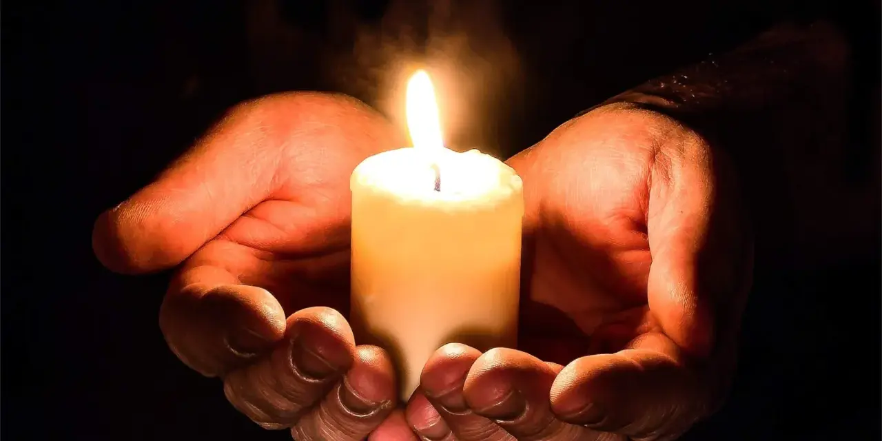 Hände umschließen eine Kerze, die ein warmes Licht spendet. Ein Symbol für evangelische Gebete und Hoffnung in der Dunkelheit.