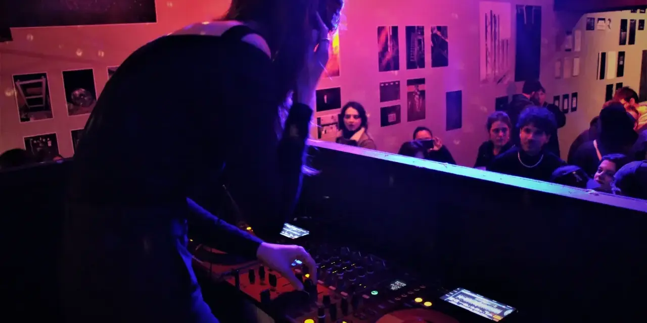 Une dj femme aux platines, ambiançant une foule dans un club.