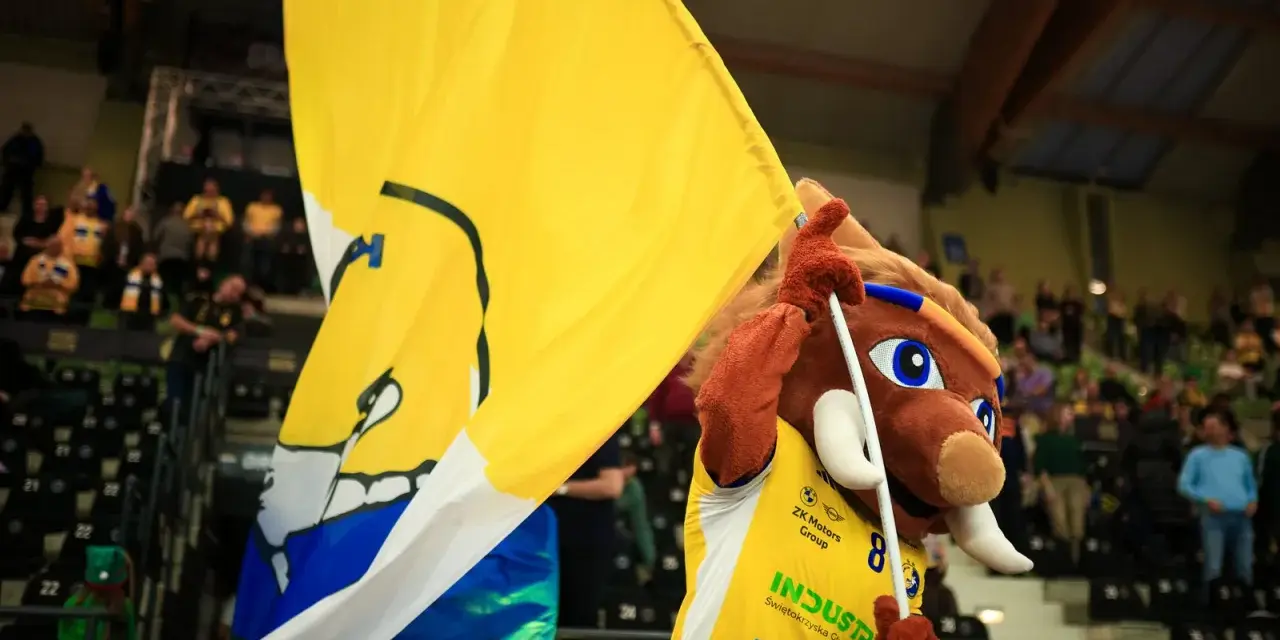 Maskotka z wielką żółtą flagą na meczu w Kielcach.