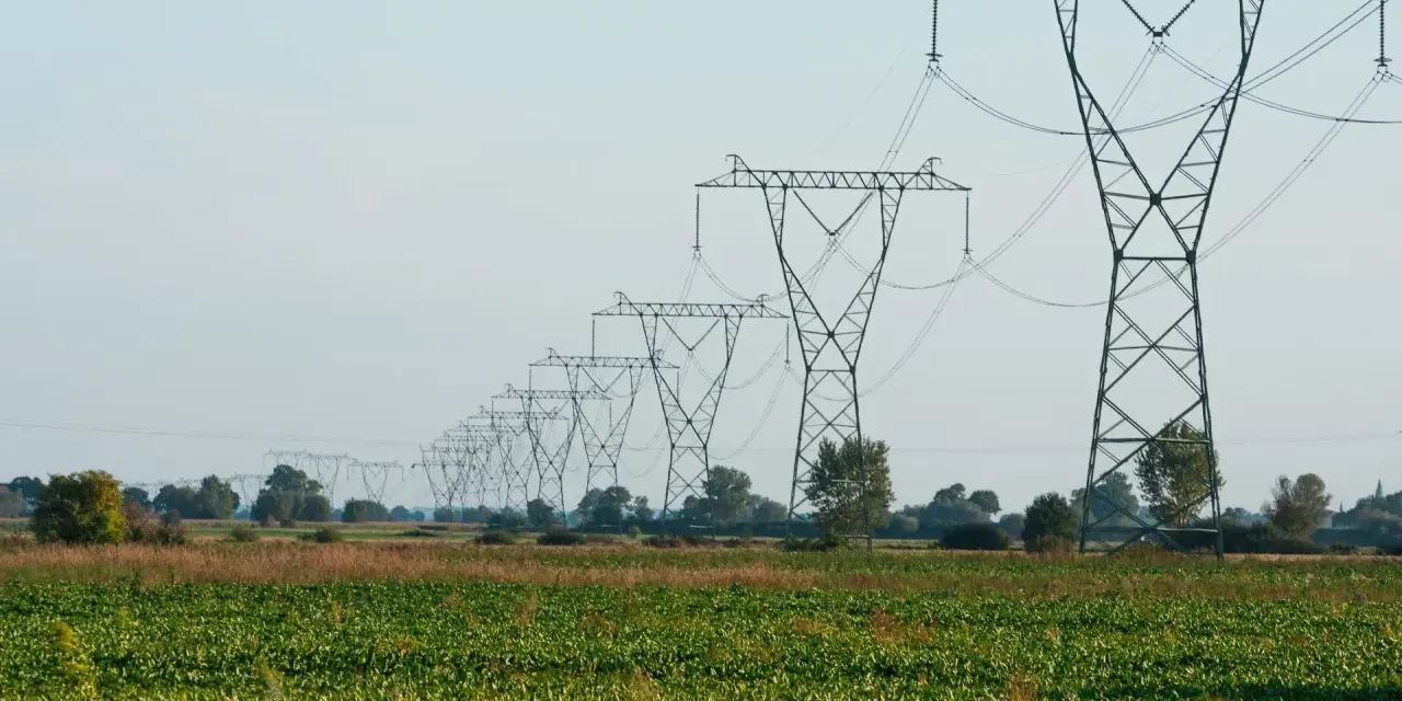 Długa linia napowietrzna ciągnie się przez zielone pole, tworząc imponujący widok.