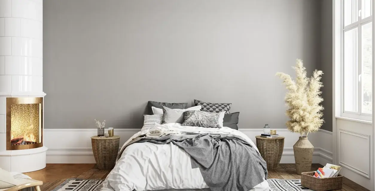 Dormitorio acogedor con chimenea encendida. El gris claro de la pared combina con blanco, negro y tonos tierra, creando un ambiente sereno.