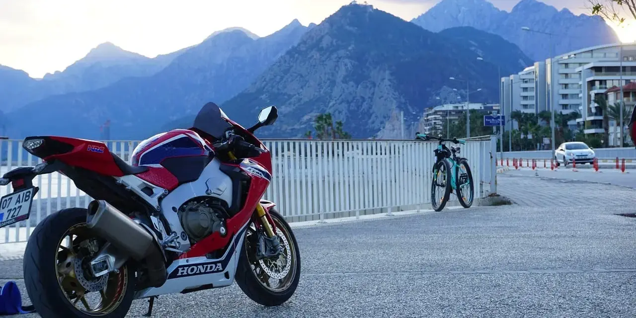 Sportowy motocykl Honda i dwa rowery na tle gór. Wyobraź sobie podróż po **tajlandii północnej** na tym sprzęcie.