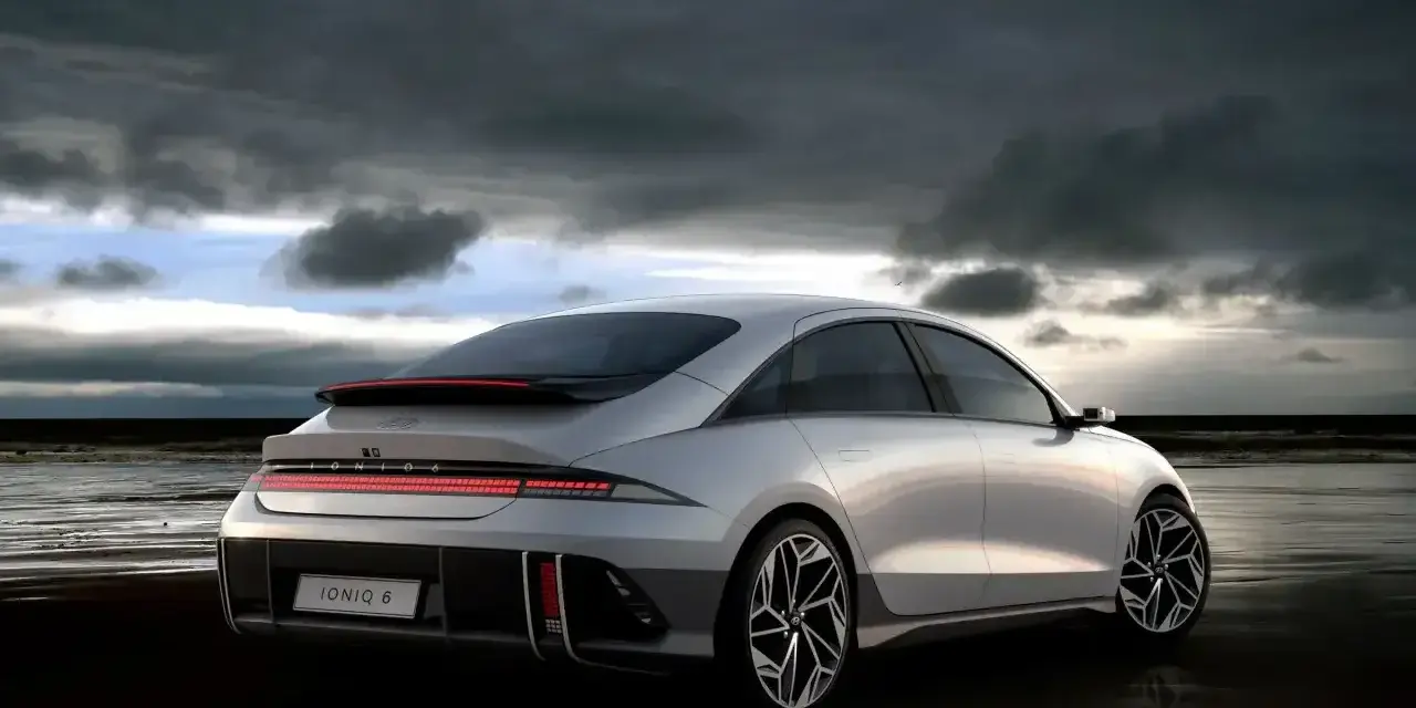 Srebrny Hyundai Ioniq 6 na plaży pod pochmurnym niebem.