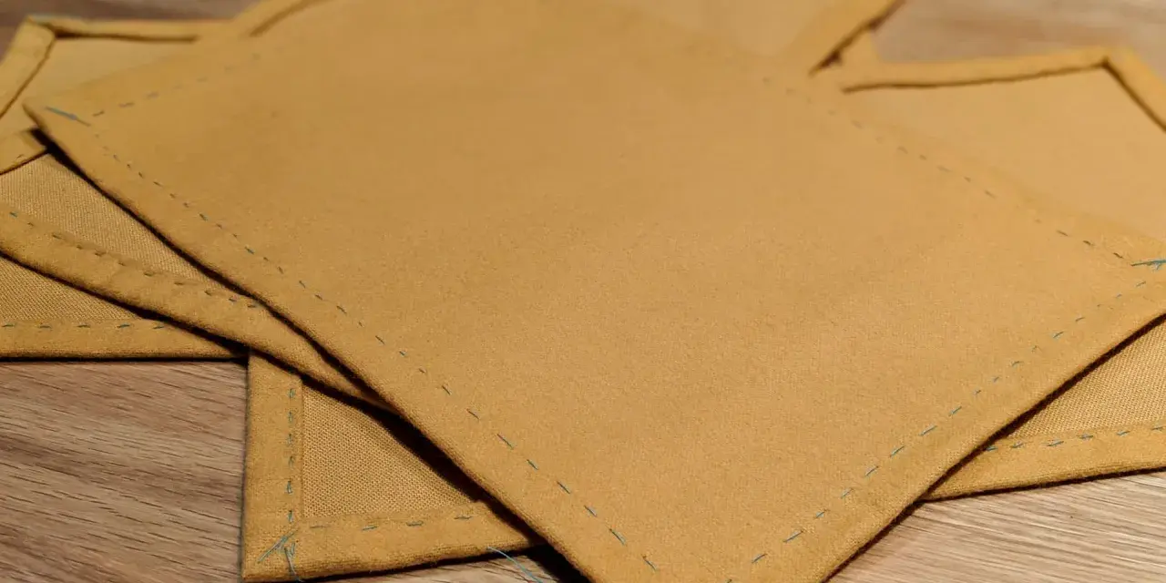 Serviettes de table en tissu ocre, finitions soignées. Idéal pour un tuto serviette de table facile à réaliser.