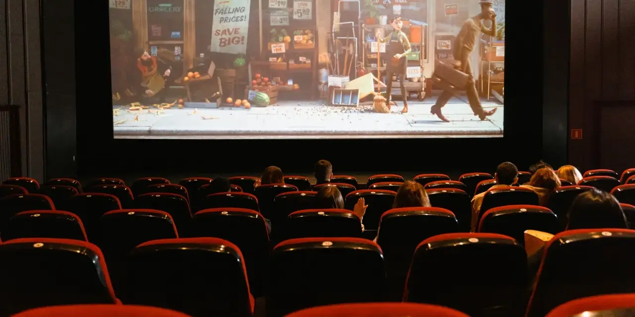 Una sala de cine con público observando una película animada. Esto es que es el cine: una experiencia compartida de historias en pantalla grande.