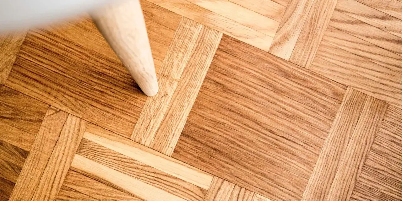 Ett vackert parkettgolv i ek, redo för renovering. En vit möbel står på golvet.
