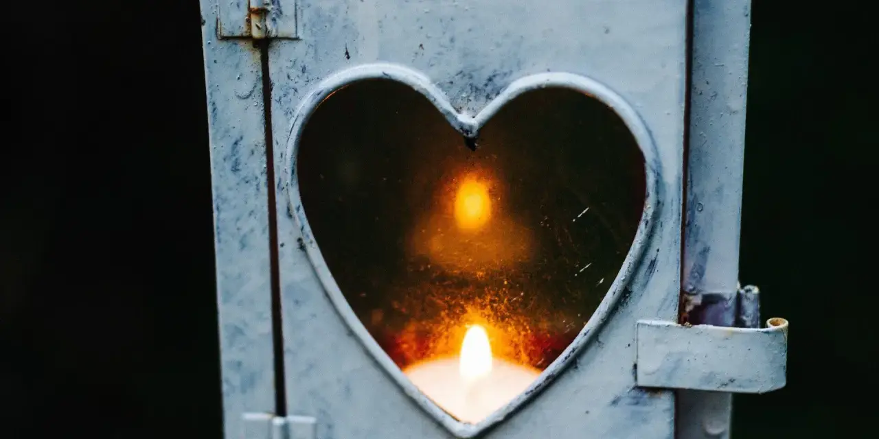 Kerze in Herzform leuchtet. Ein Symbol der Erinnerung an die gestorbene Oma.