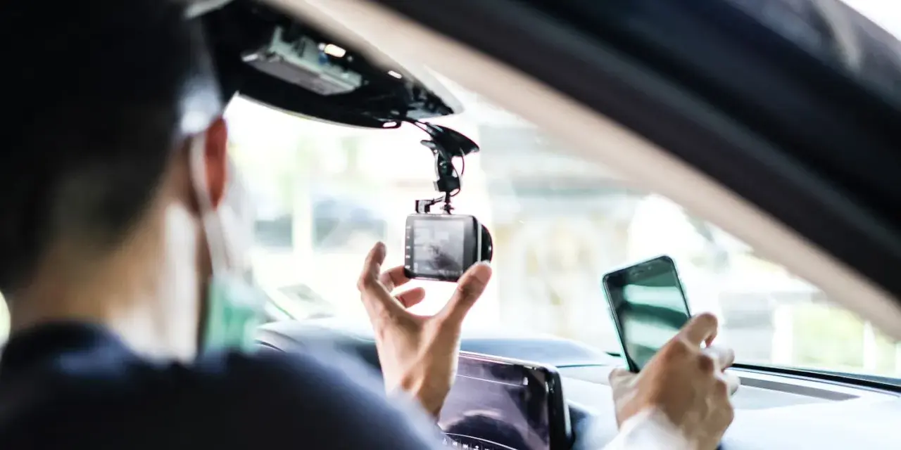 Mann installiert Dashcam im Auto, ADAC-Mitglieder profitieren von sicherer Fahrt.