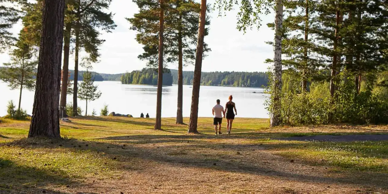 Ett par promenerar hand i hand vid en sjö, en idyllisk plats som påminner om det första camp ansia.