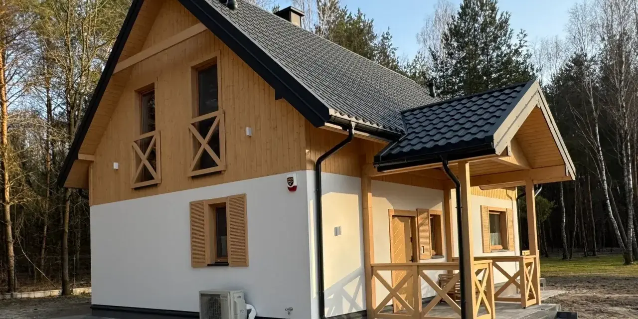 Nowy dom w lesie, drewniane elementy i biały tynk. Prowadzenie budowy domu zakończone sukcesem, gotowy do zamieszkania.